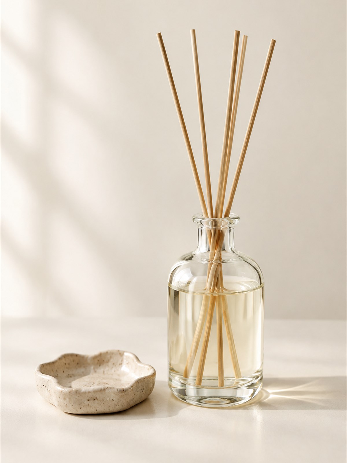 Amber glass reed diffuser with rattan reeds on a wooden shelf